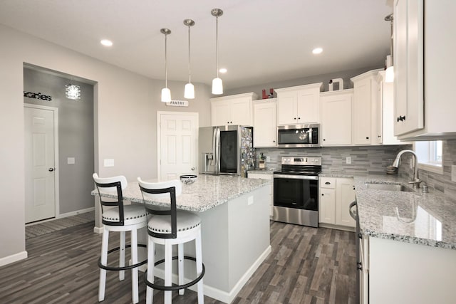 kitchen featuring appliances with stainless steel finishes, a kitchen island, a sink, and white cabinets