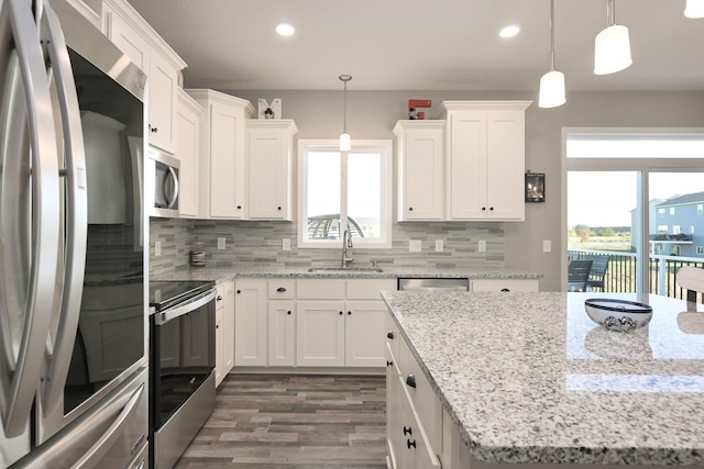 kitchen featuring stainless steel appliances, white cabinets, hanging light fixtures, and a sink