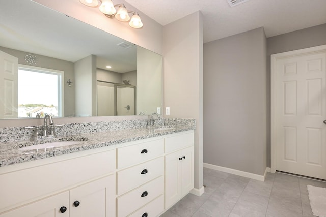 full bath featuring a stall shower, a sink, baseboards, and double vanity