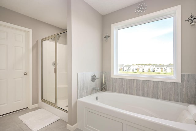 bathroom featuring a stall shower, a garden tub, and tile patterned floors