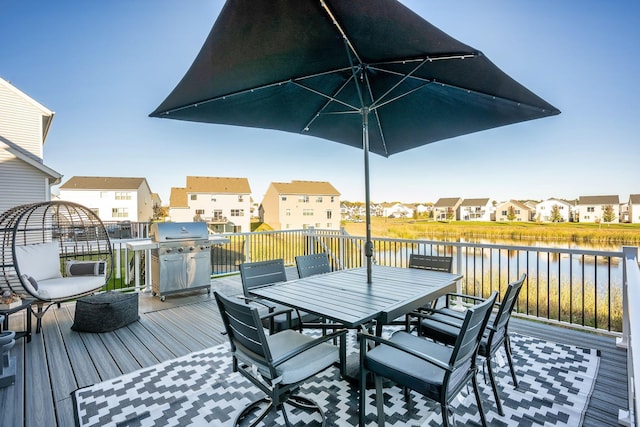 wooden deck featuring a water view, a grill, a residential view, and outdoor dining area