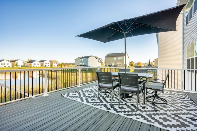 wooden terrace with a residential view, a water view, and outdoor dining space