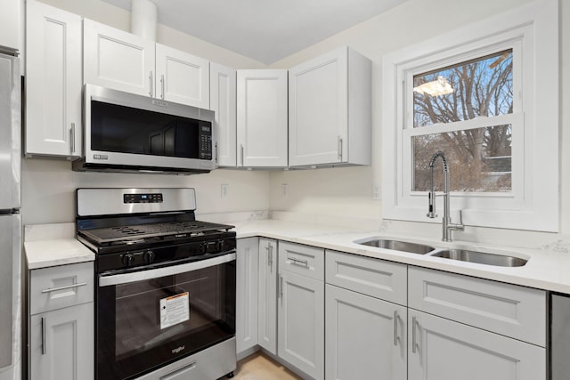 kitchen with light stone countertops, stainless steel appliances, white cabinetry, and sink