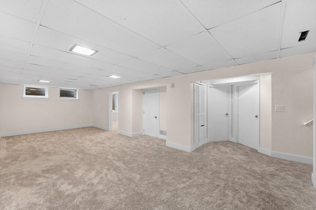 basement with a paneled ceiling and light carpet