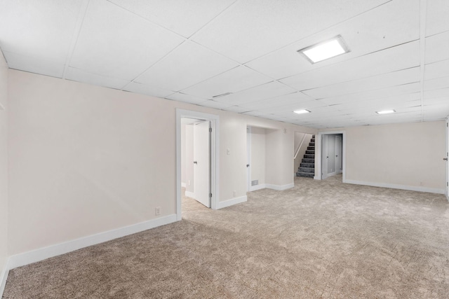 basement featuring light colored carpet and a drop ceiling