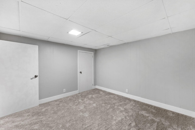 basement with a paneled ceiling and carpet