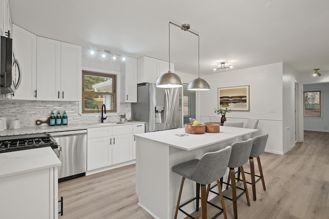 kitchen featuring white cabinets, appliances with stainless steel finishes, a kitchen island, decorative backsplash, and sink