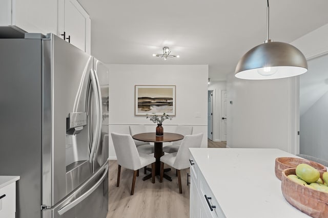 kitchen featuring stainless steel refrigerator with ice dispenser, decorative light fixtures, white cabinets, and light hardwood / wood-style floors