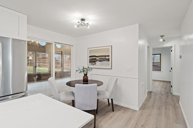 dining space with an inviting chandelier and light hardwood / wood-style flooring