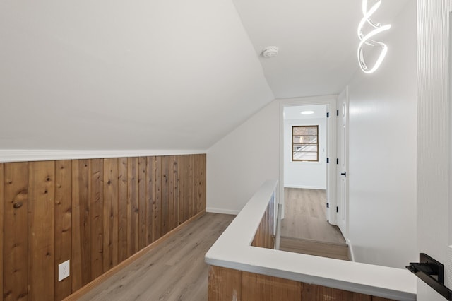 interior space with wood walls, lofted ceiling, and light hardwood / wood-style flooring