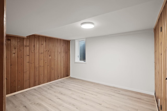 basement featuring light hardwood / wood-style flooring and wooden walls