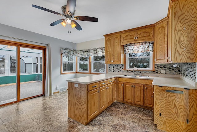 kitchen featuring kitchen peninsula, ceiling fan, backsplash, and sink