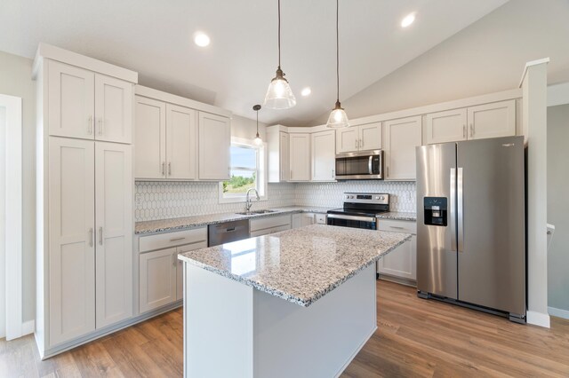 kitchen featuring hanging light fixtures, a kitchen island, white cabinetry, appliances with stainless steel finishes, and sink