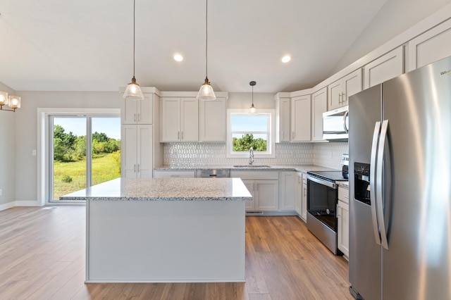 kitchen featuring pendant lighting, a center island, tasteful backsplash, white cabinetry, and appliances with stainless steel finishes