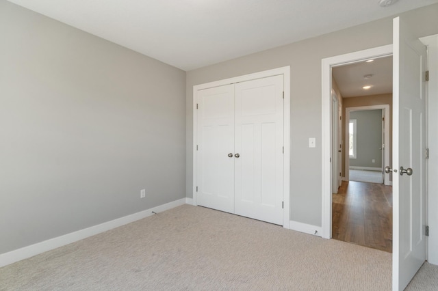 unfurnished bedroom with light colored carpet and a closet