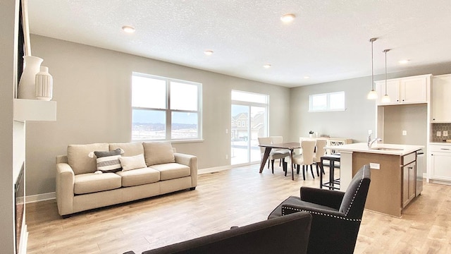 living room with sink, a textured ceiling, and light hardwood / wood-style flooring