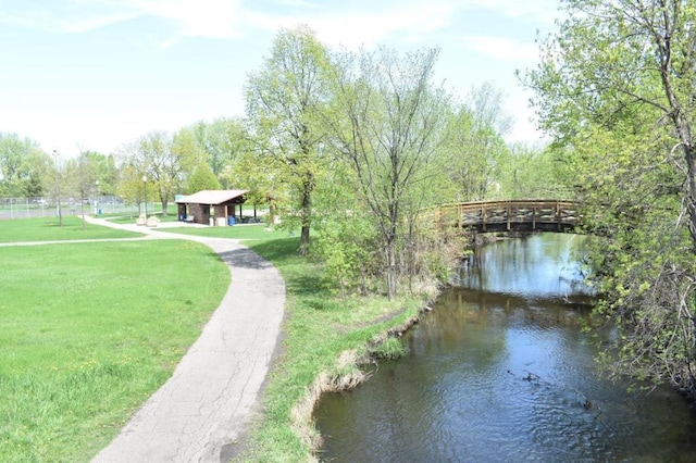 surrounding community with a water view and a yard