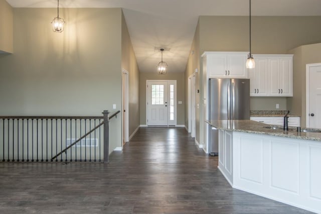 kitchen featuring light stone counters, hanging light fixtures, dark hardwood / wood-style flooring, white cabinetry, and sink