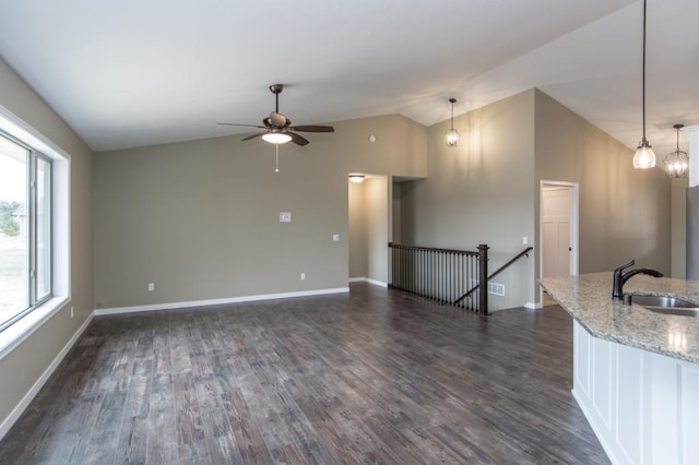 unfurnished living room with ceiling fan with notable chandelier, dark wood-type flooring, vaulted ceiling, and sink