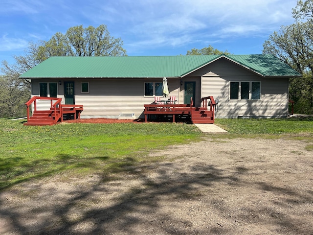 back of house with a deck, metal roof, and a lawn