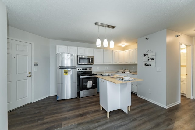 kitchen featuring white cabinetry, appliances with stainless steel finishes, dark wood-type flooring, hanging light fixtures, and a center island