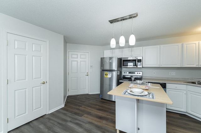 kitchen with decorative light fixtures, a kitchen island, white cabinetry, appliances with stainless steel finishes, and a textured ceiling