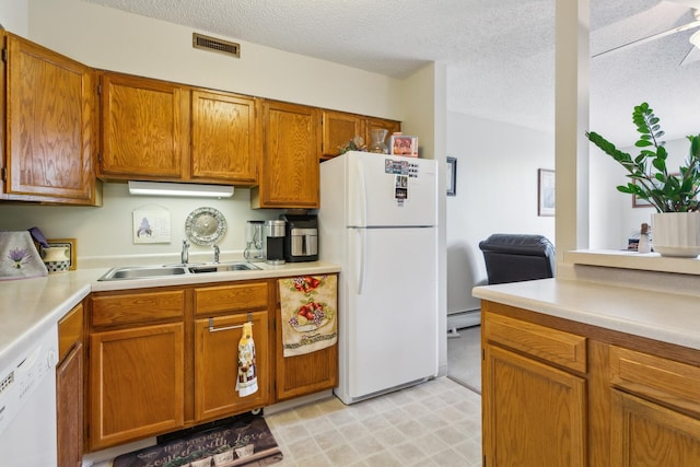 kitchen featuring white appliances, sink, a textured ceiling, and a baseboard heating unit