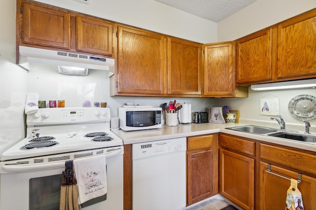 kitchen with white appliances, sink, and a textured ceiling