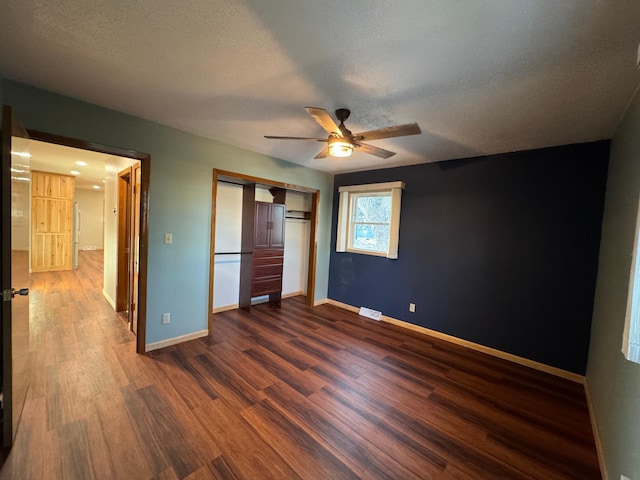 unfurnished bedroom with dark hardwood / wood-style floors, a textured ceiling, ceiling fan, and a closet