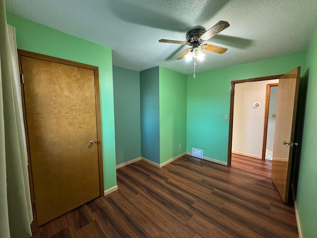 unfurnished bedroom featuring ceiling fan, dark hardwood / wood-style flooring, a closet, and a textured ceiling