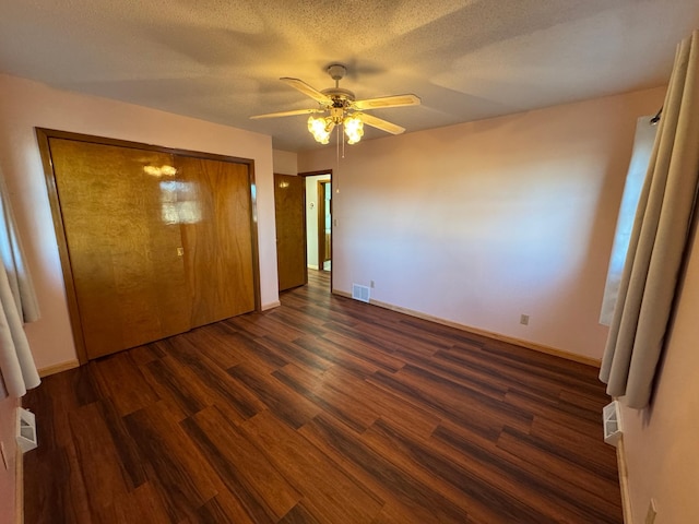 unfurnished bedroom featuring ceiling fan, dark hardwood / wood-style flooring, a closet, and a textured ceiling