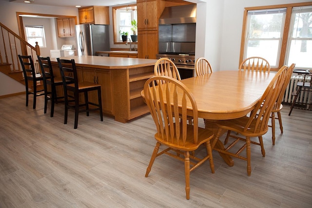 dining space featuring light wood-type flooring, a healthy amount of sunlight, and sink