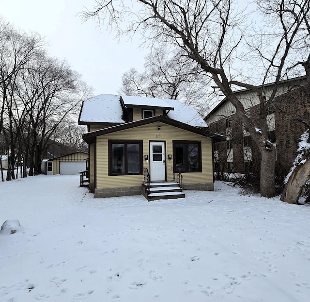 bungalow-style home with a garage and an outbuilding