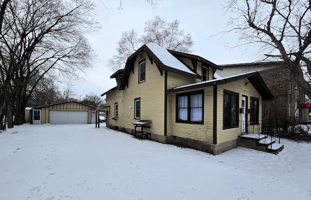 view of snowy exterior with a garage and an outbuilding