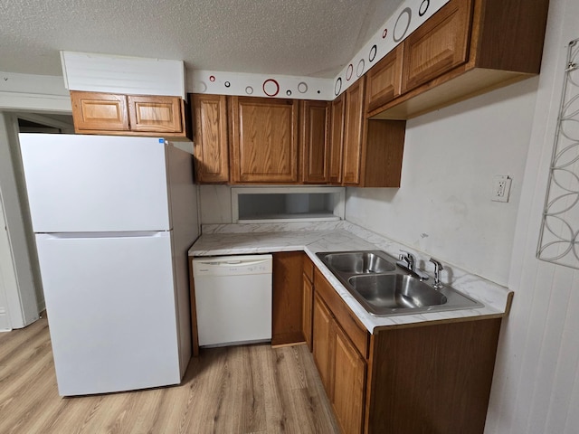 kitchen with white appliances, a textured ceiling, light hardwood / wood-style flooring, and sink