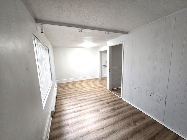 interior space featuring a textured ceiling, hardwood / wood-style floors, wooden walls, and beamed ceiling