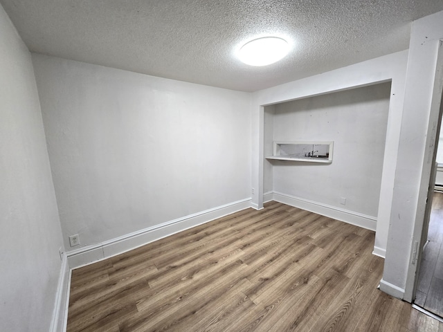 spare room with a textured ceiling and wood-type flooring