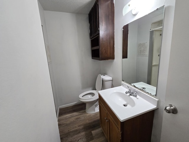 bathroom featuring a textured ceiling, toilet, vanity, and wood-type flooring