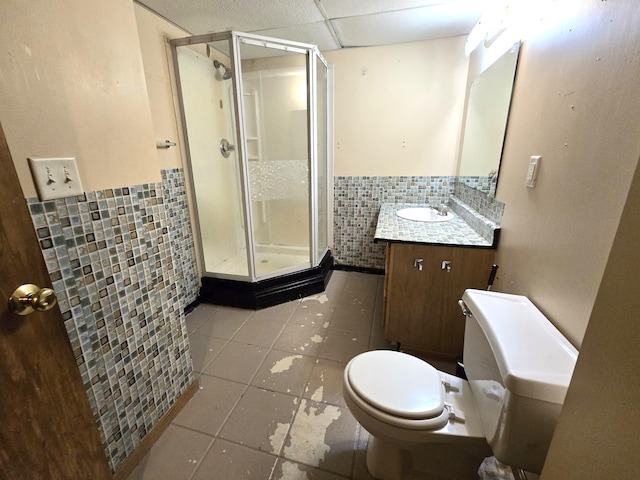 bathroom with tile patterned flooring, tile walls, a shower with shower door, toilet, and vanity