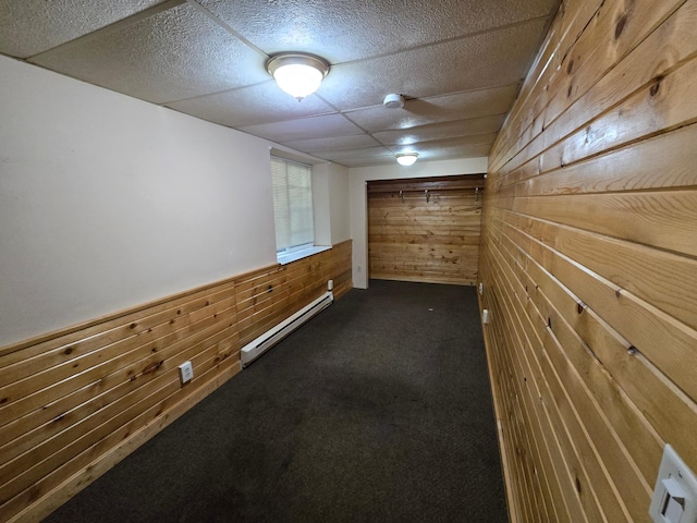 interior space with a baseboard radiator, wood walls, and dark colored carpet