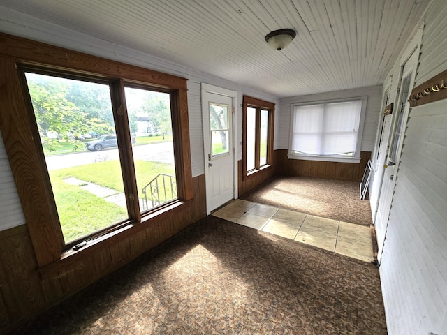 doorway with light colored carpet and wood walls