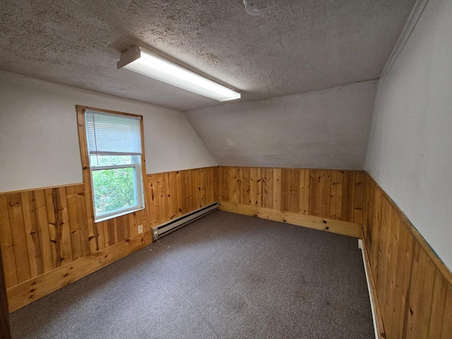 additional living space featuring a textured ceiling, baseboard heating, lofted ceiling, and dark colored carpet