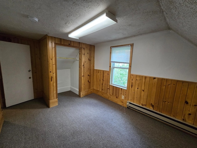 bonus room with a textured ceiling, lofted ceiling, wood walls, dark colored carpet, and a baseboard radiator