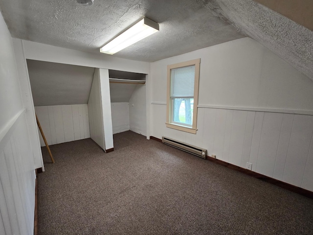 bonus room with vaulted ceiling, dark colored carpet, wooden walls, a textured ceiling, and a baseboard radiator