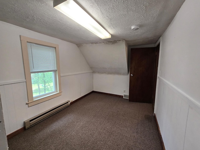 additional living space featuring a baseboard heating unit, a textured ceiling, dark colored carpet, and vaulted ceiling