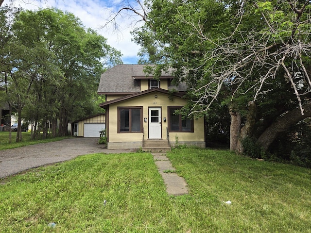 view of front of house with a front yard, a garage, and an outdoor structure