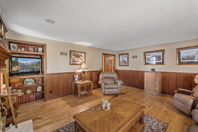 living area with a wainscoted wall, light wood-style flooring, and wood walls