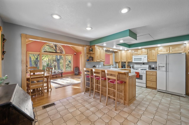 kitchen with white appliances, a breakfast bar, open shelves, light countertops, and a peninsula