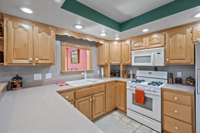 kitchen with white appliances, a sink, light countertops, and recessed lighting
