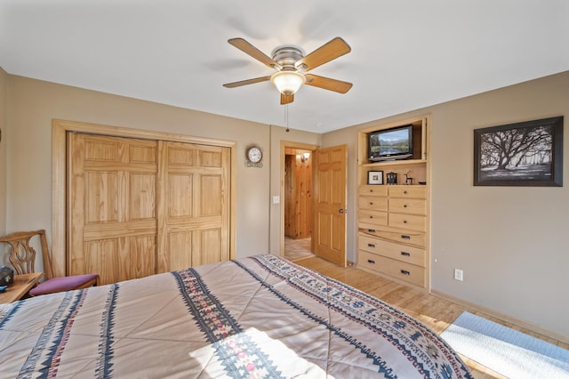 bedroom with wood finished floors, a closet, baseboards, and a ceiling fan